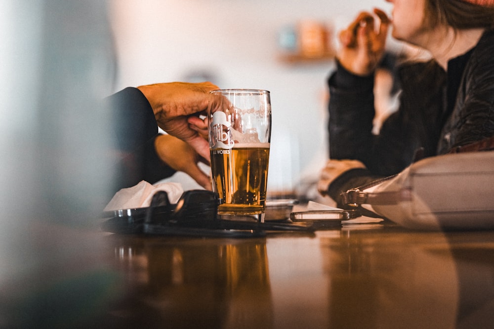 two people sitting at a table with a glass of beer