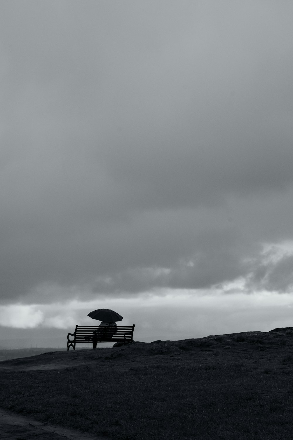 une photo en noir et blanc d’un banc avec un parapluie