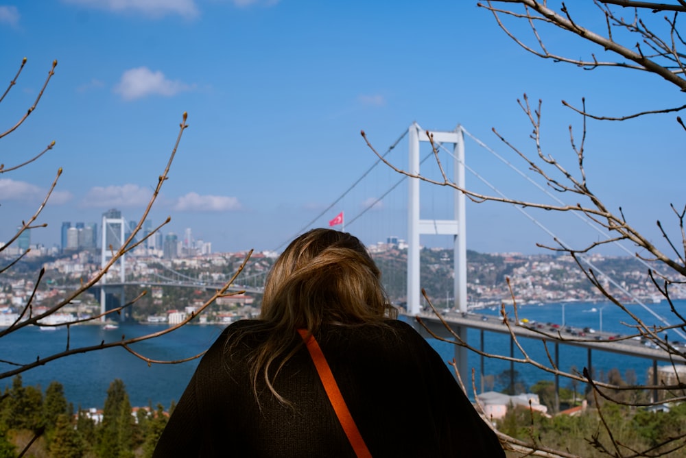a woman is looking at the view of a bridge