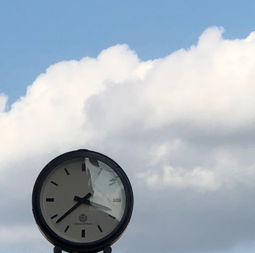 a clock on top of a pole in front of a cloudy sky