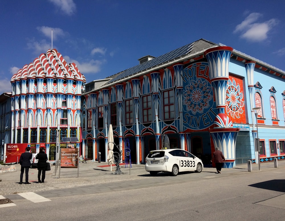 a white car parked in front of a colorful building