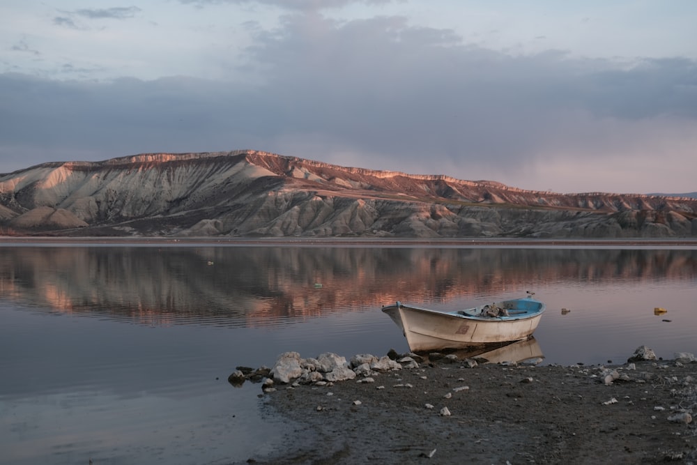 a boat sitting on the shore of a lake