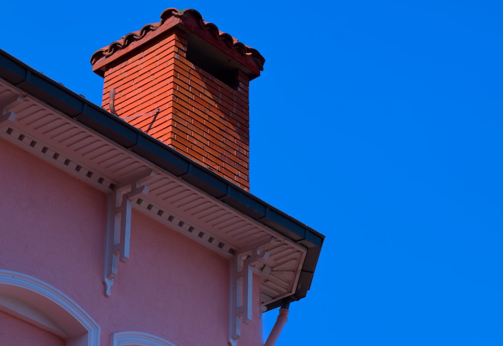 a brick chimney on top of a pink building