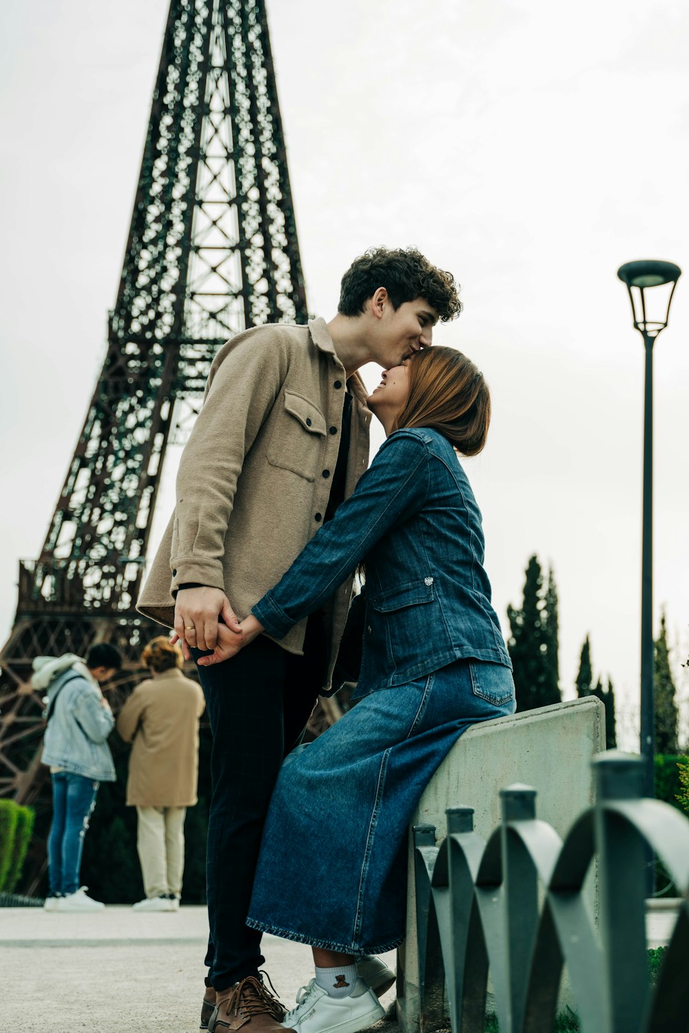 a man and woman kissing in front of the eiffel tower
