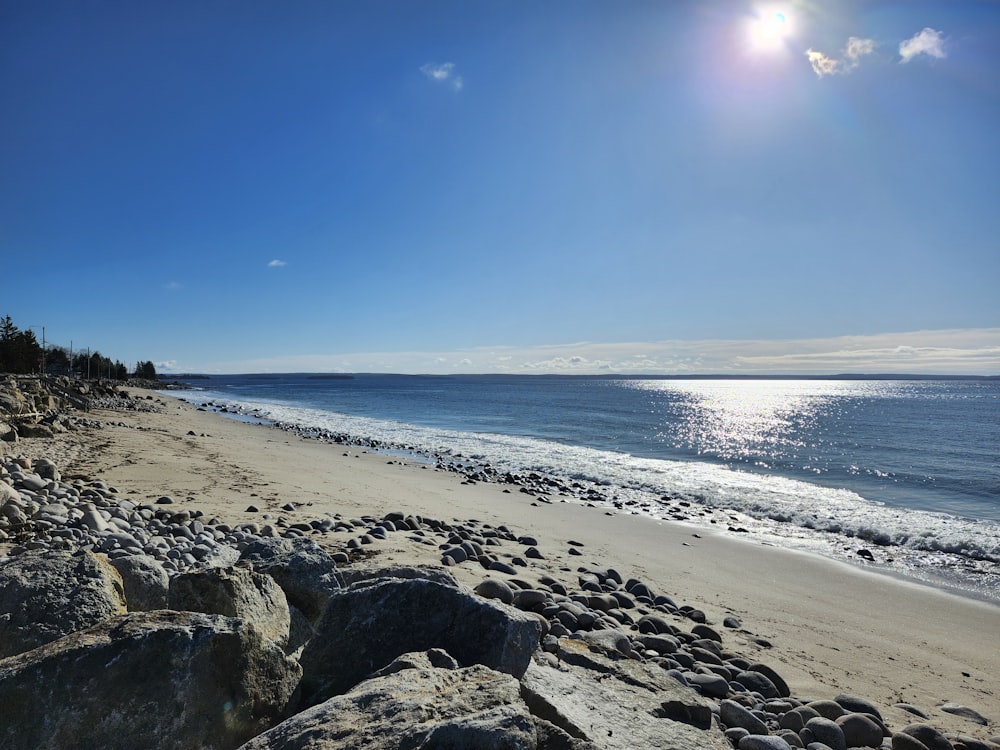 the sun shines brightly over a rocky beach