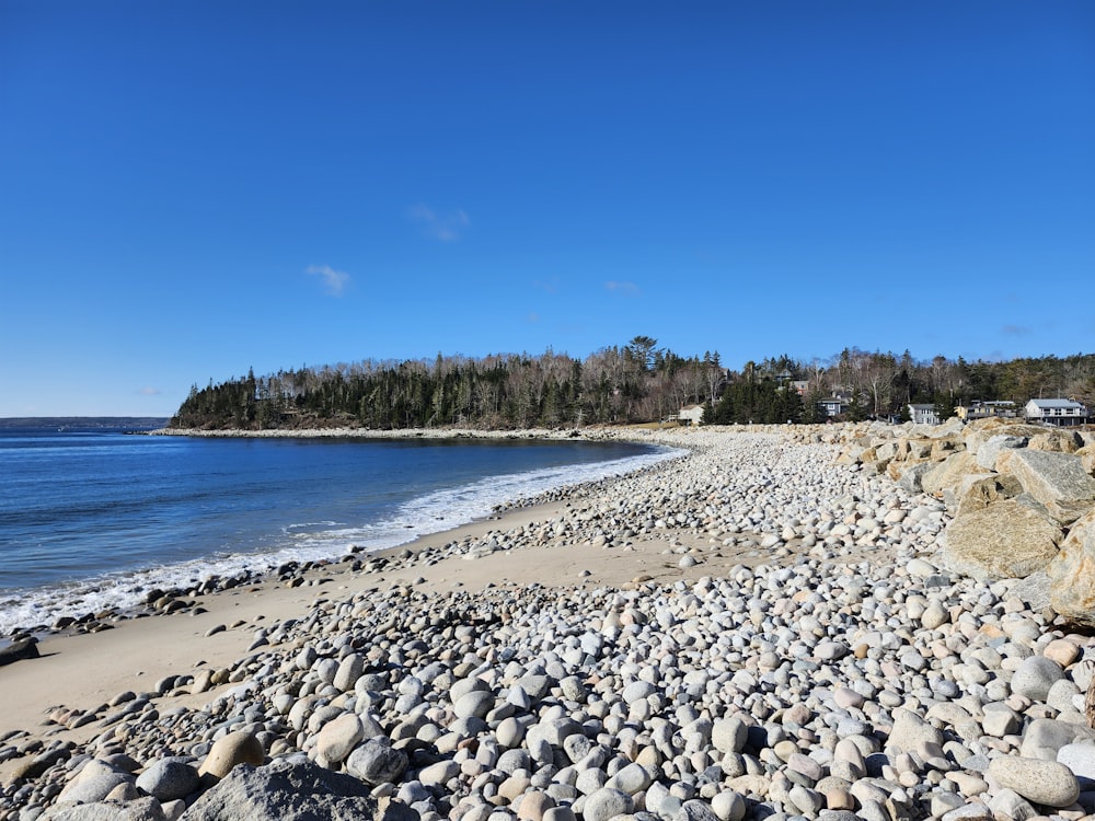 a beach with rocks and water on a sunny day