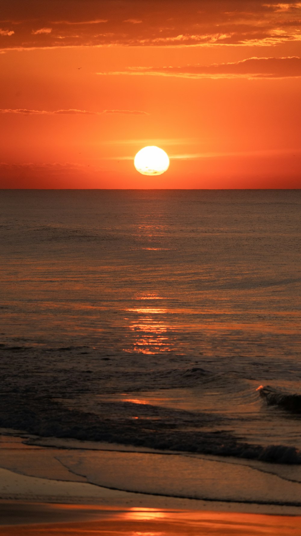 the sun is setting over the ocean on the beach