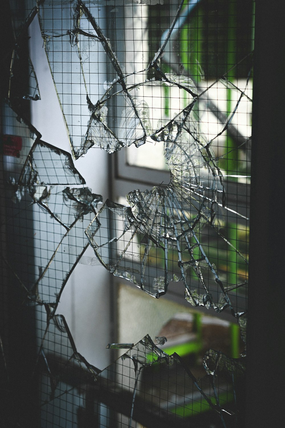 a broken glass door with a window in the background