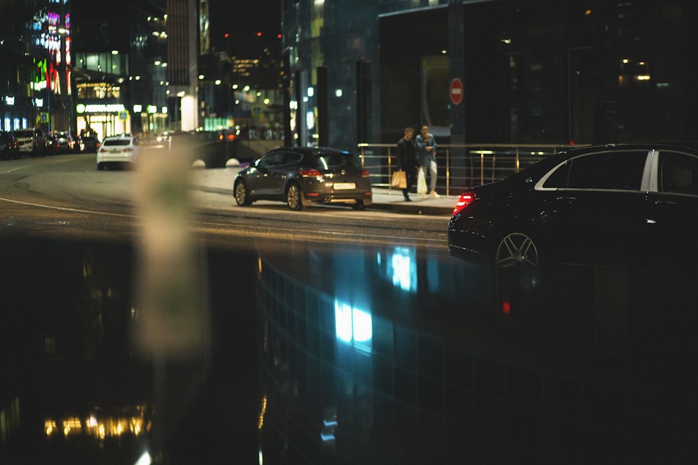 a city street at night with cars parked on the side of the road