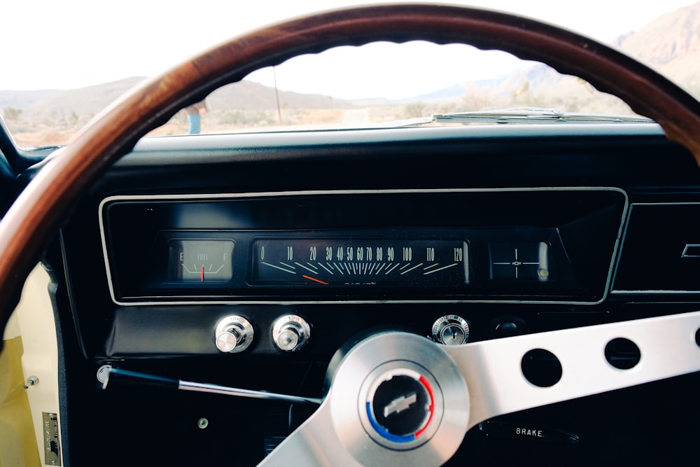 the dashboard of a car with a wooden steering wheel
