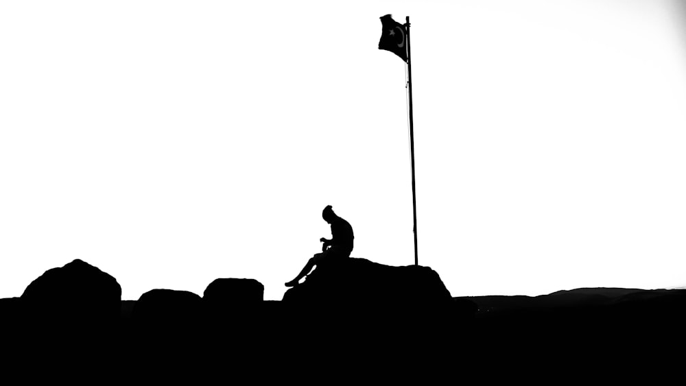 a black and white photo of a person on top of a rock