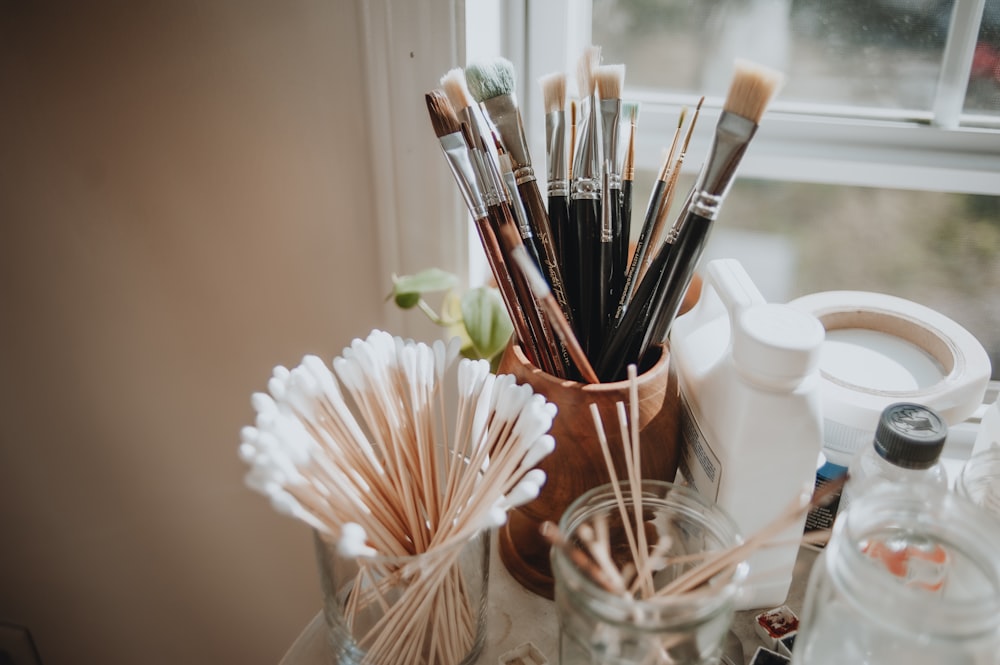 a vase filled with lots of brushes next to a window