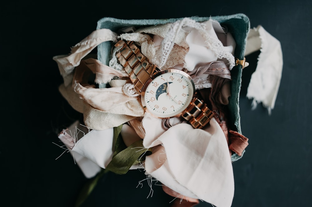 a watch sitting on top of a pile of scarves