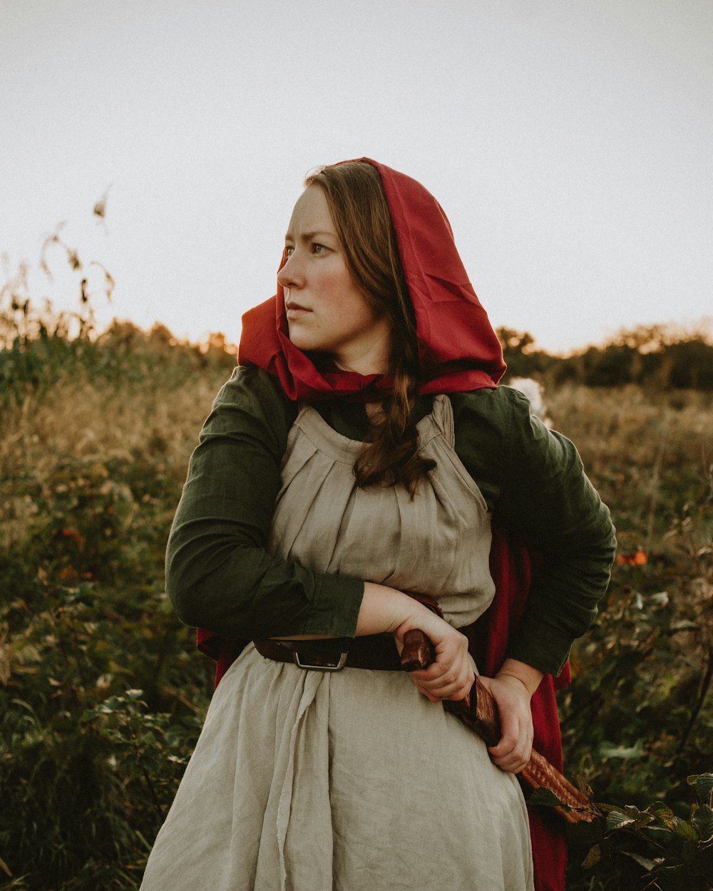 a woman in a red hoodie is standing in a field