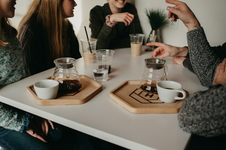 Group of friends laughing together over coffee at an outdoor cafe table