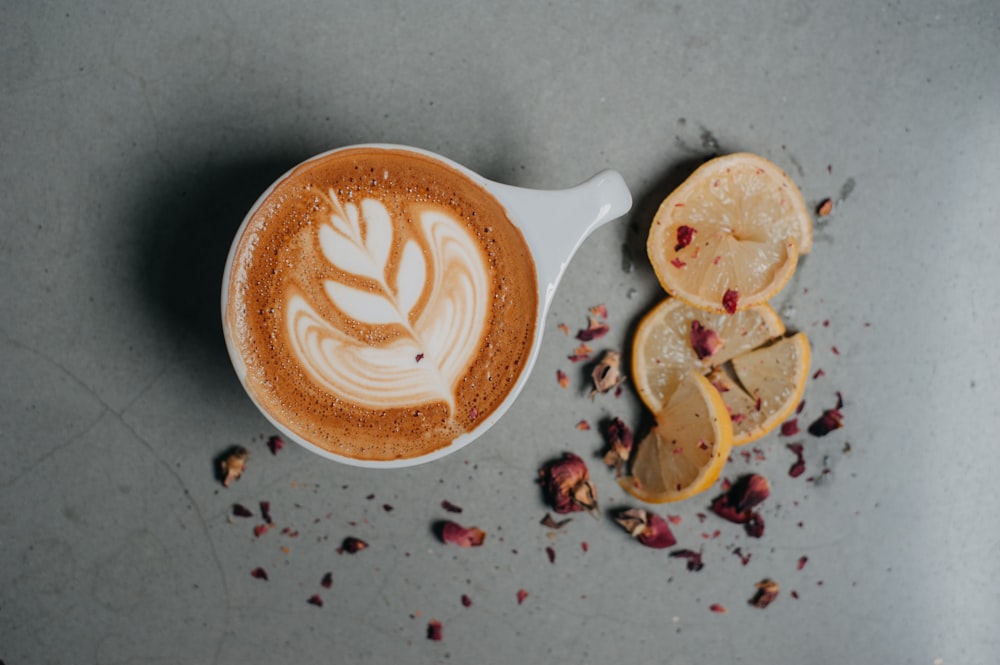 a cup of cappuccino with orange slices on the side