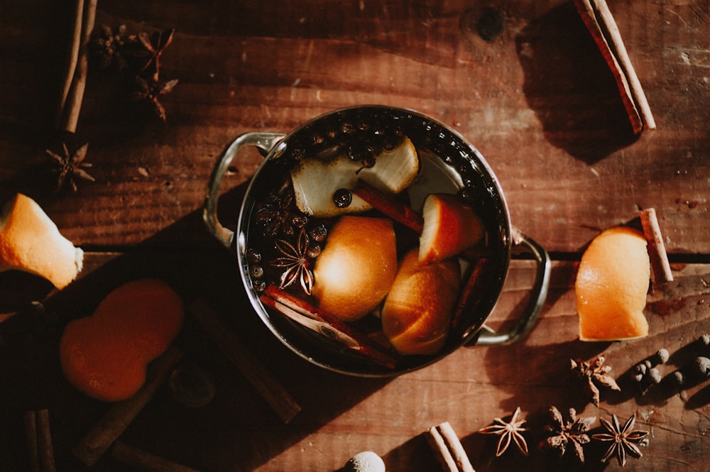 apples and cinnamons in a pot on a wooden table