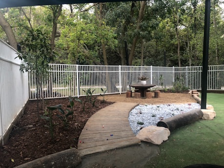 a backyard with a wooden deck and a white fence