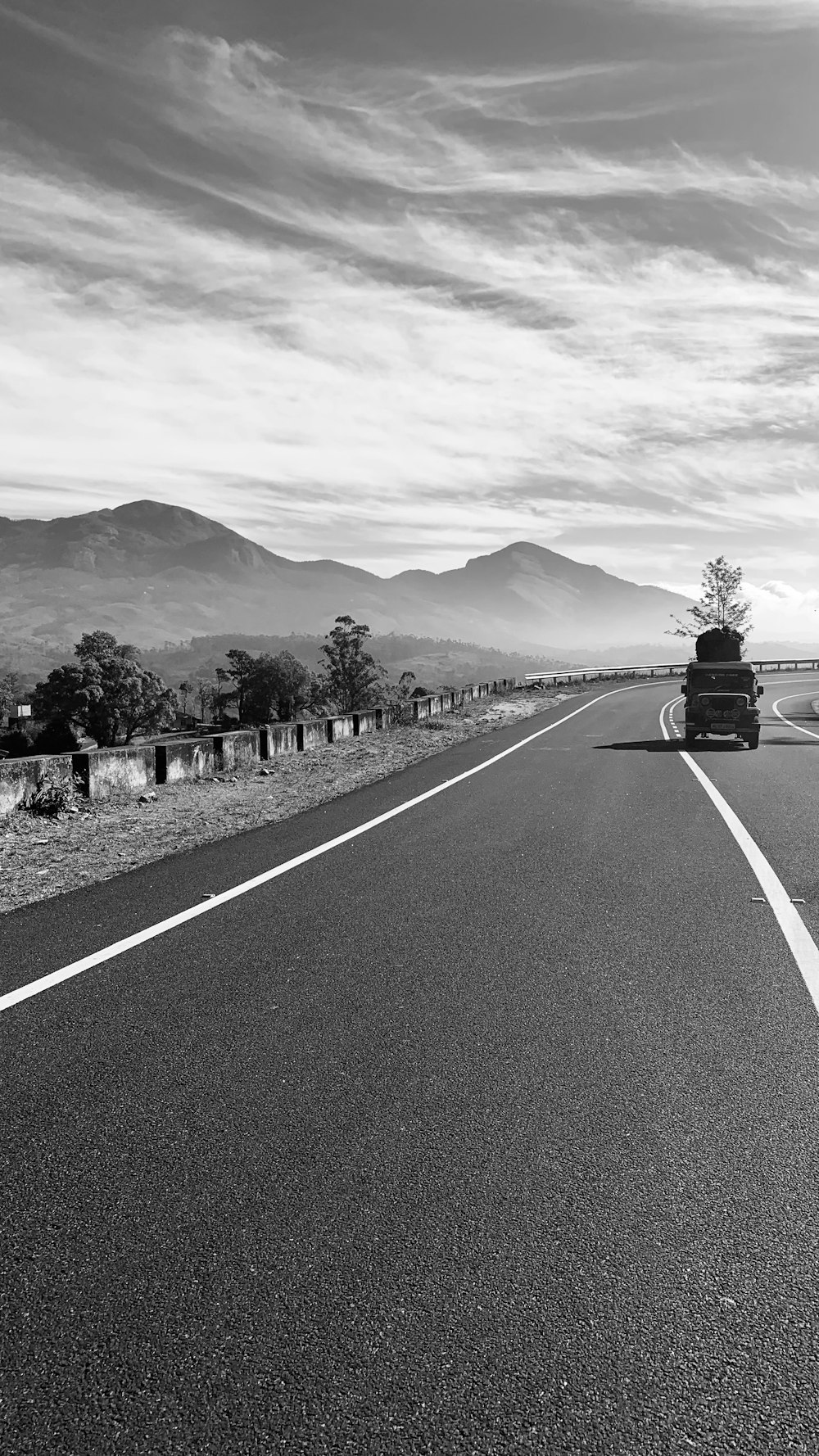 a black and white photo of a truck driving down the road