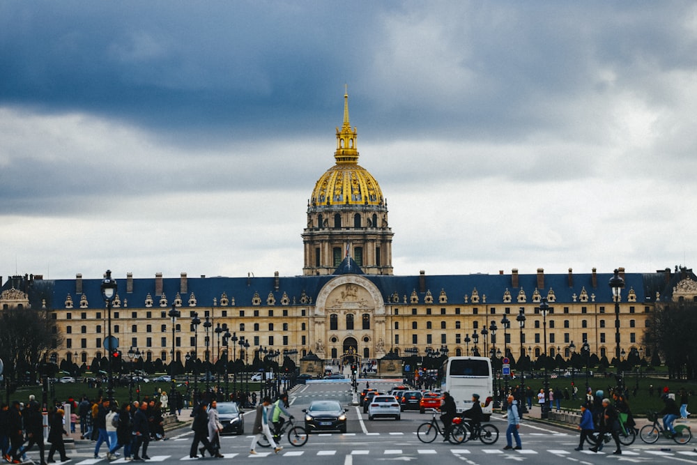 a group of people crossing a street in front of a large building