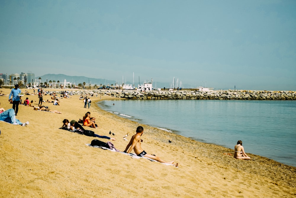 a group of people sitting on top of a sandy beach