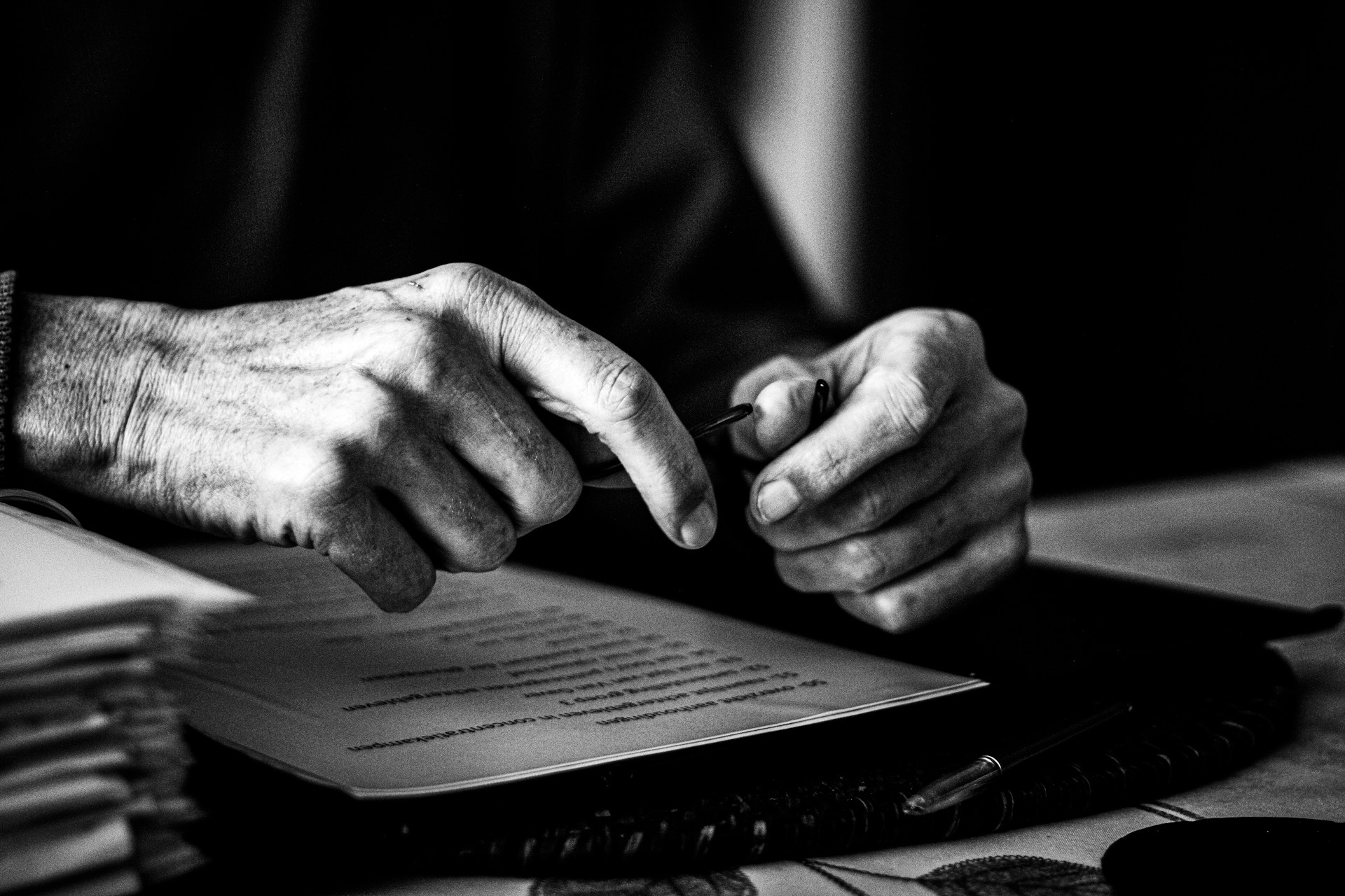 a black and white photo of a person's hands on a book