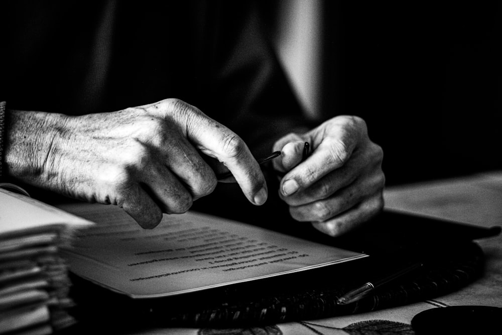 a black and white photo of a person's hands on a book