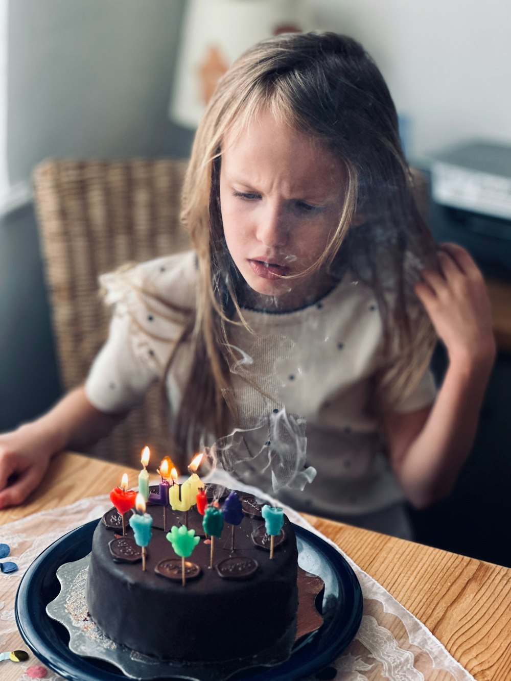 a young girl blowing out candles on a chocolate cake