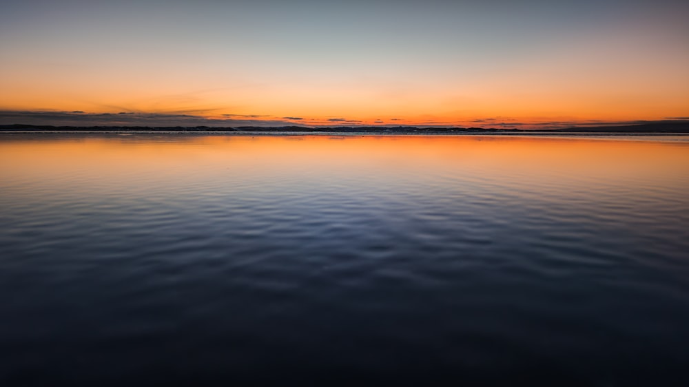 a large body of water with a sunset in the background