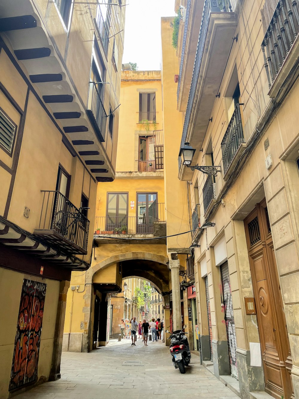 a narrow city street with a motorcycle parked on the side of it