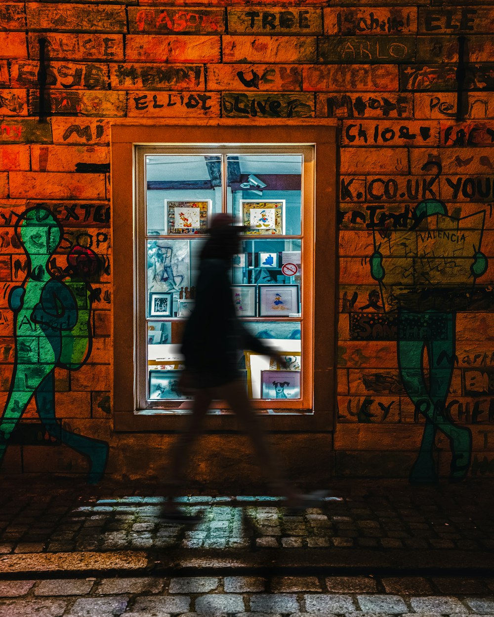 a person walking past a window with graffiti on it