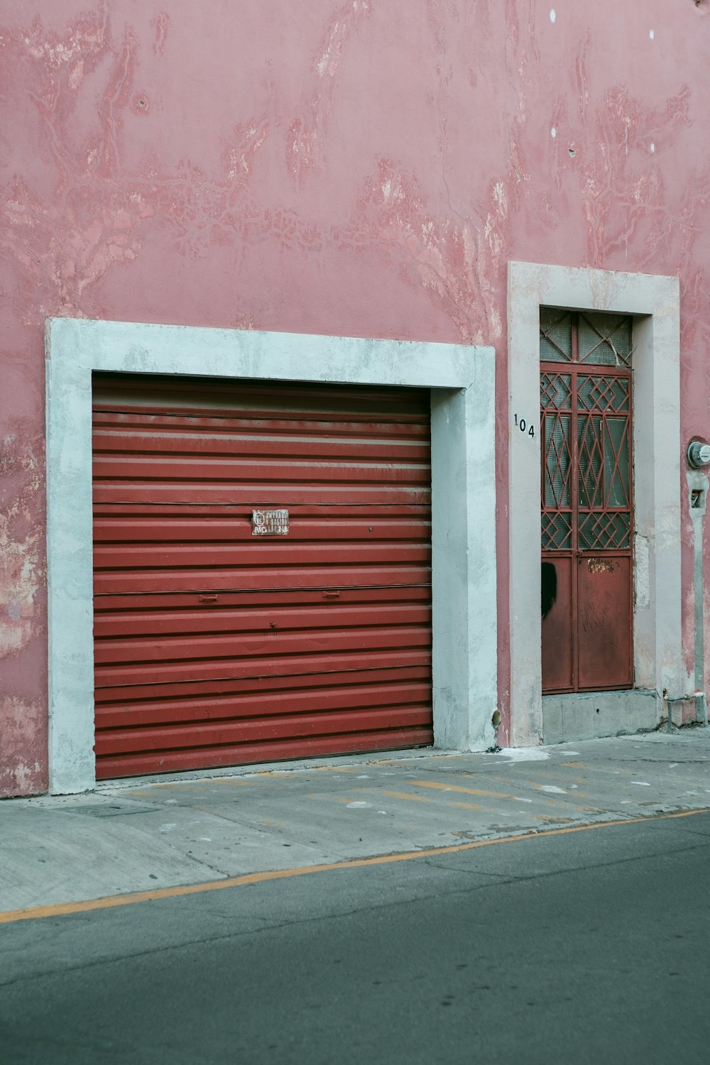 a red garage door on the side of a pink building