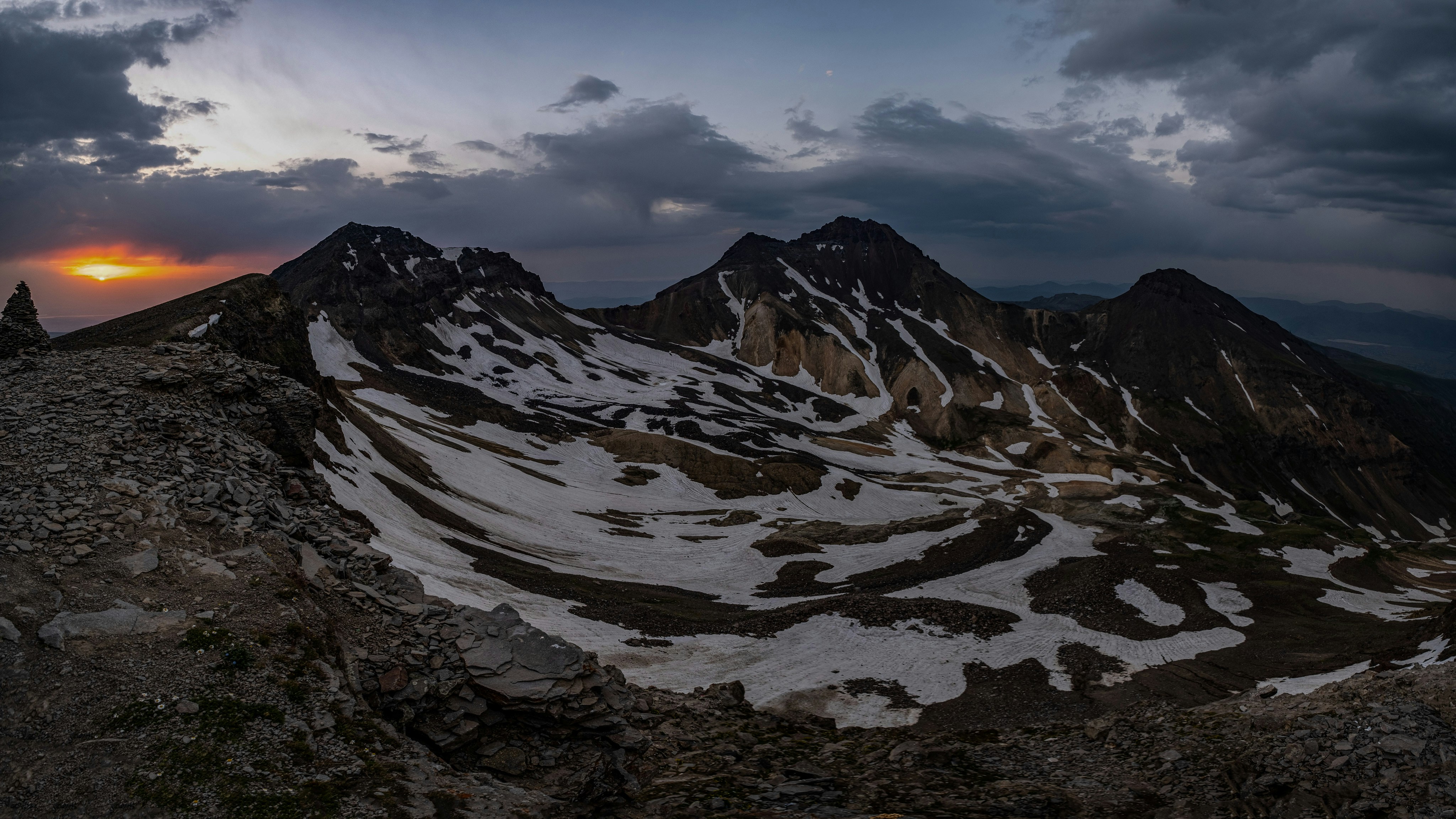 the sun is setting over a snowy mountain