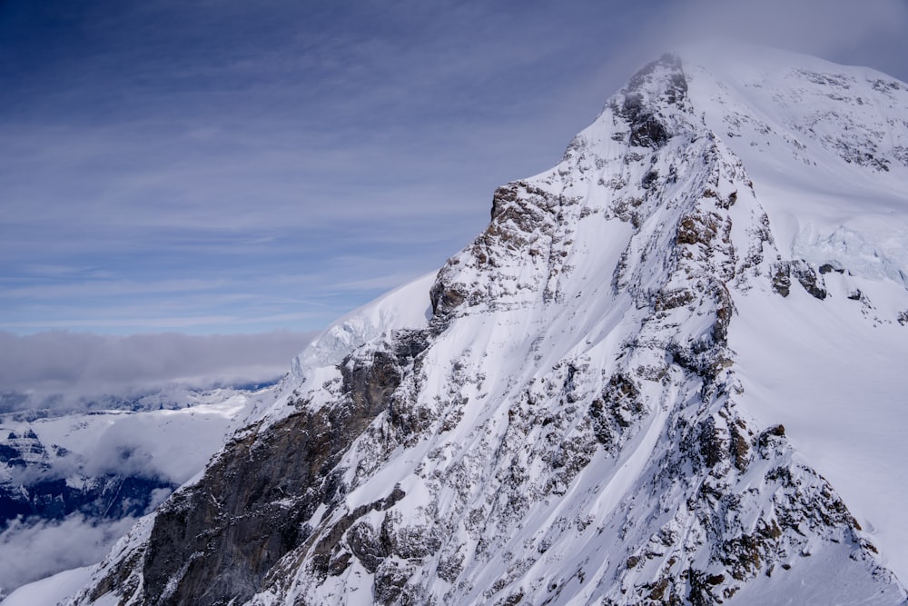 a snow covered mountain peak with clouds in the background