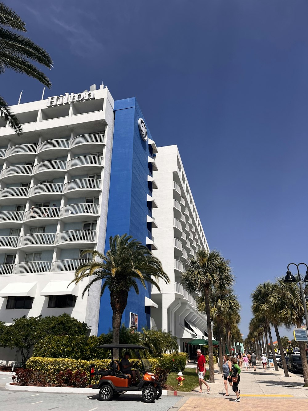 a blue and white hotel with palm trees in front of it