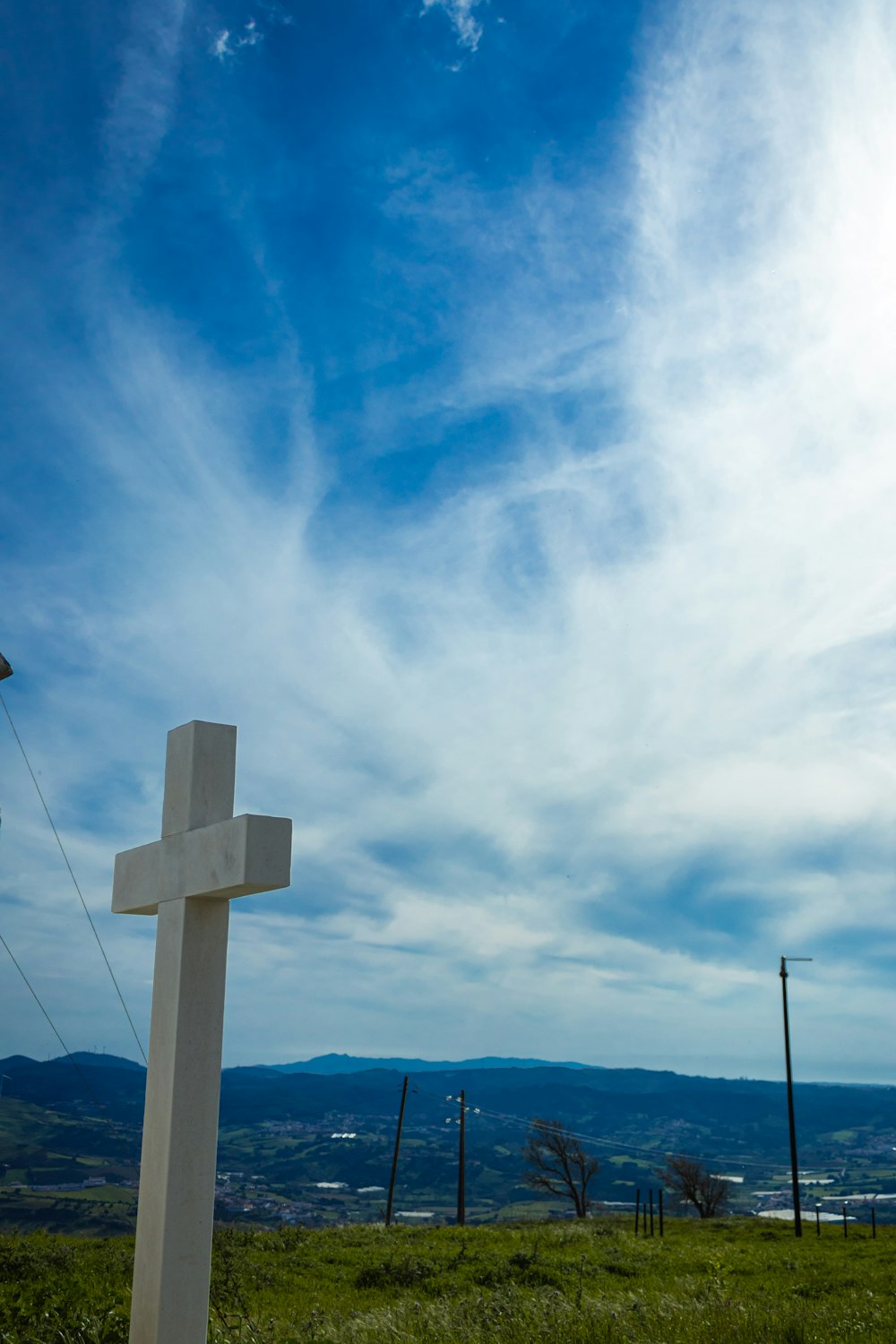 a white cross sitting in the middle of a lush green field