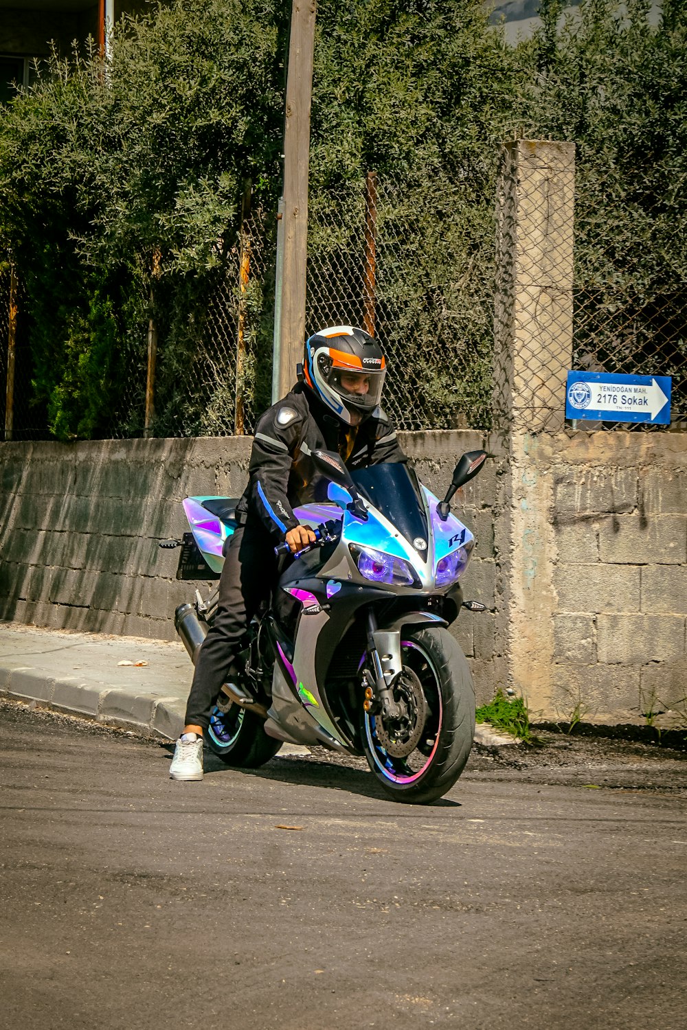 a man riding a motorcycle down a street next to a fence