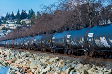 a long train on a steel track next to a body of water