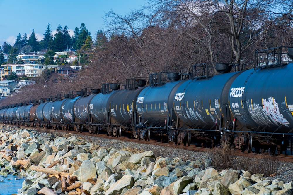 a long train on a steel track next to a body of water