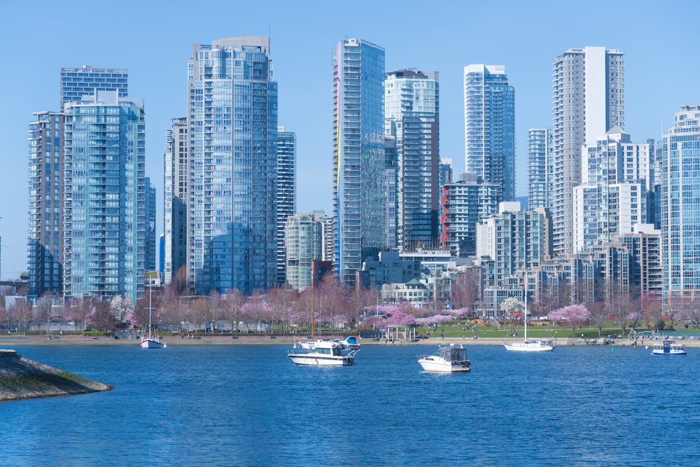 a group of boats floating on top of a lake next to tall buildings