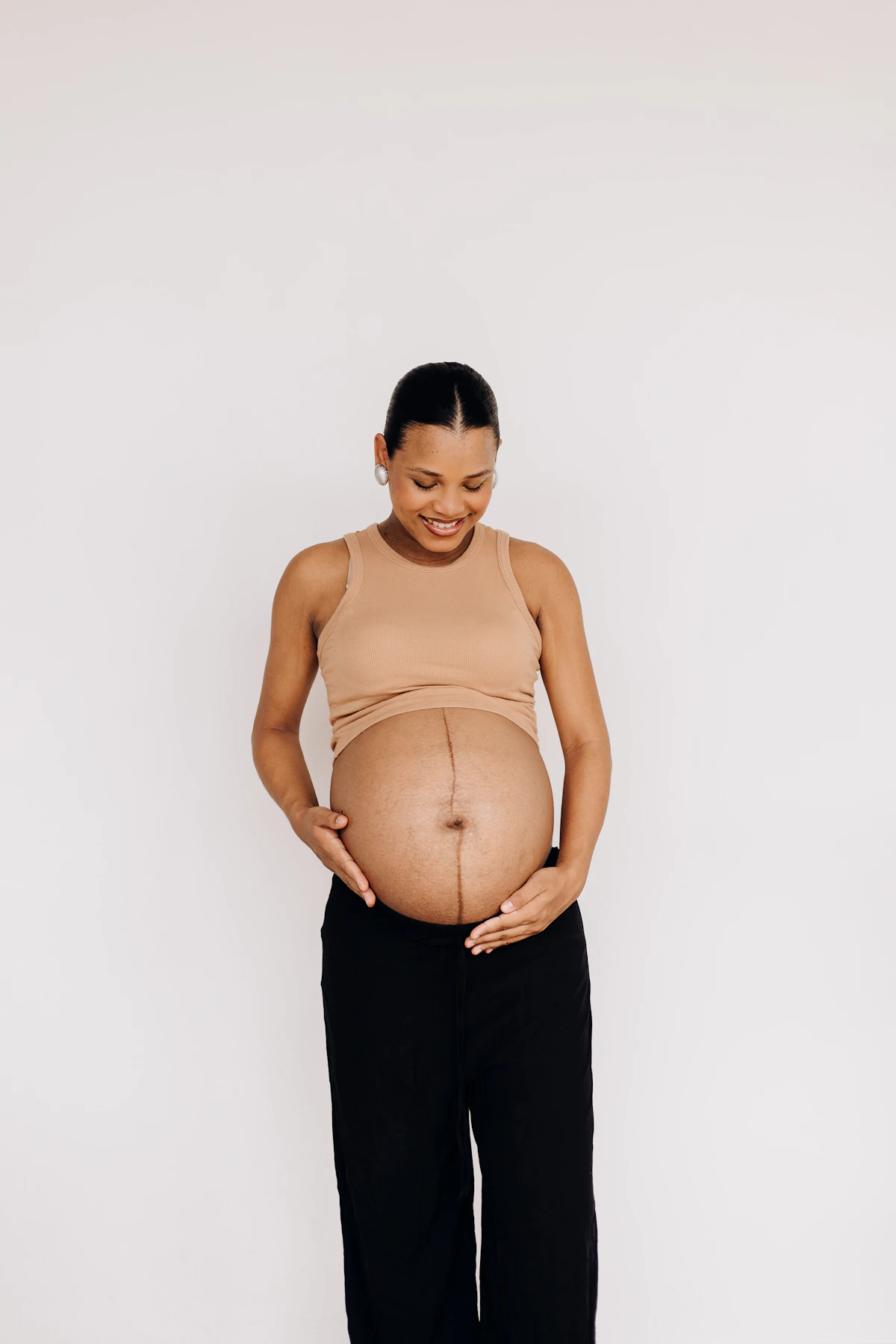 Pregnant woman standing with her hands on her belly