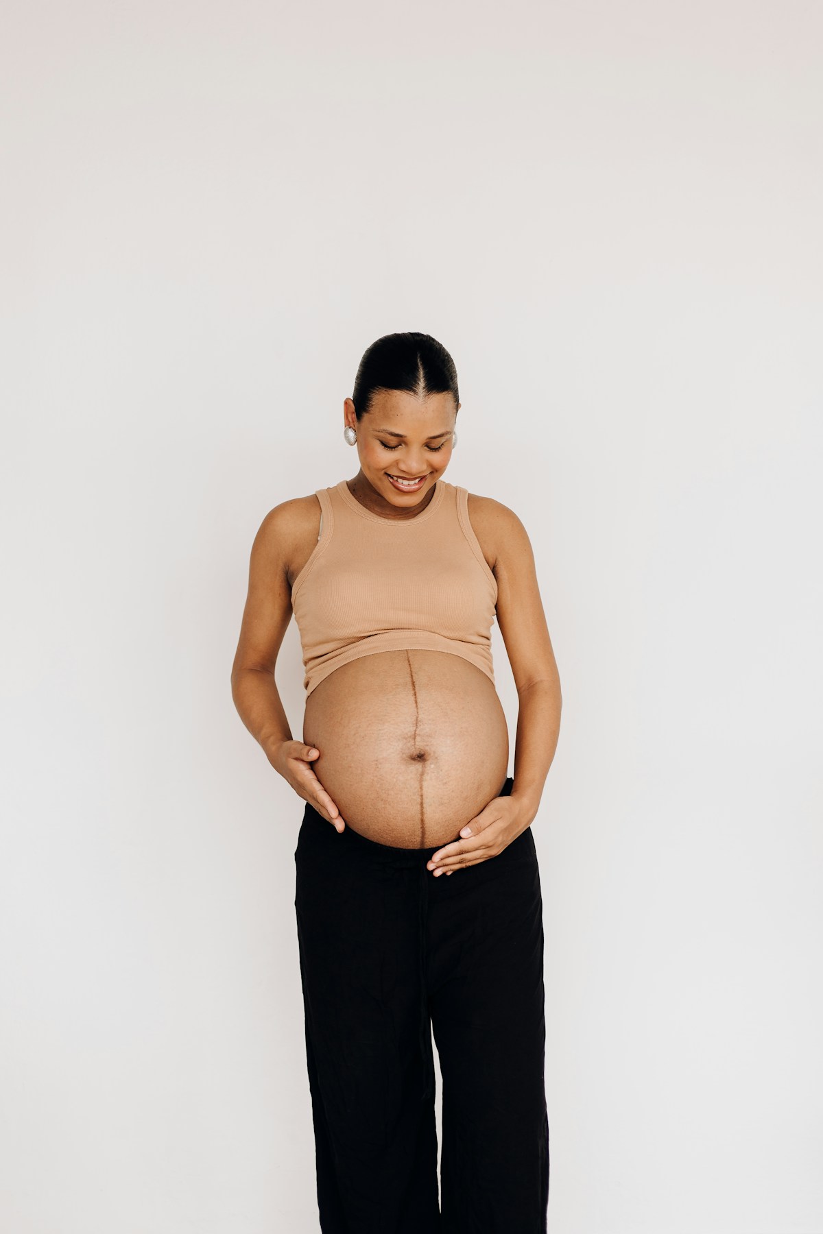 Femme enceinte portant une longue chaîne dont le pendentif repose sur son ventre