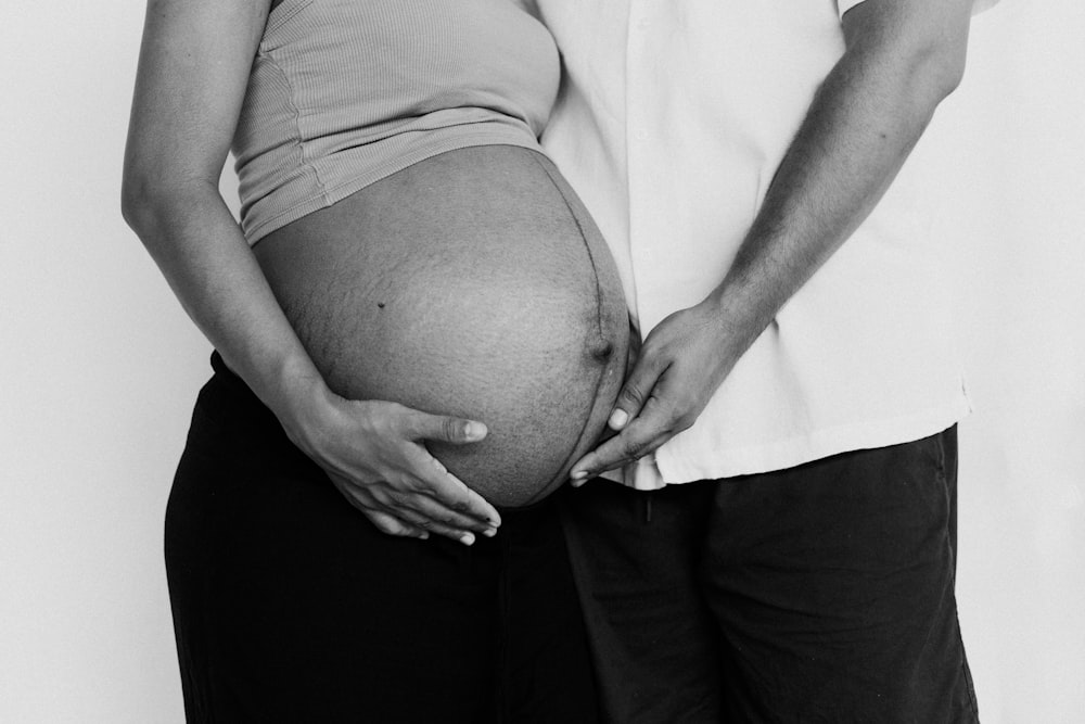 a man and a woman holding their pregnant belly