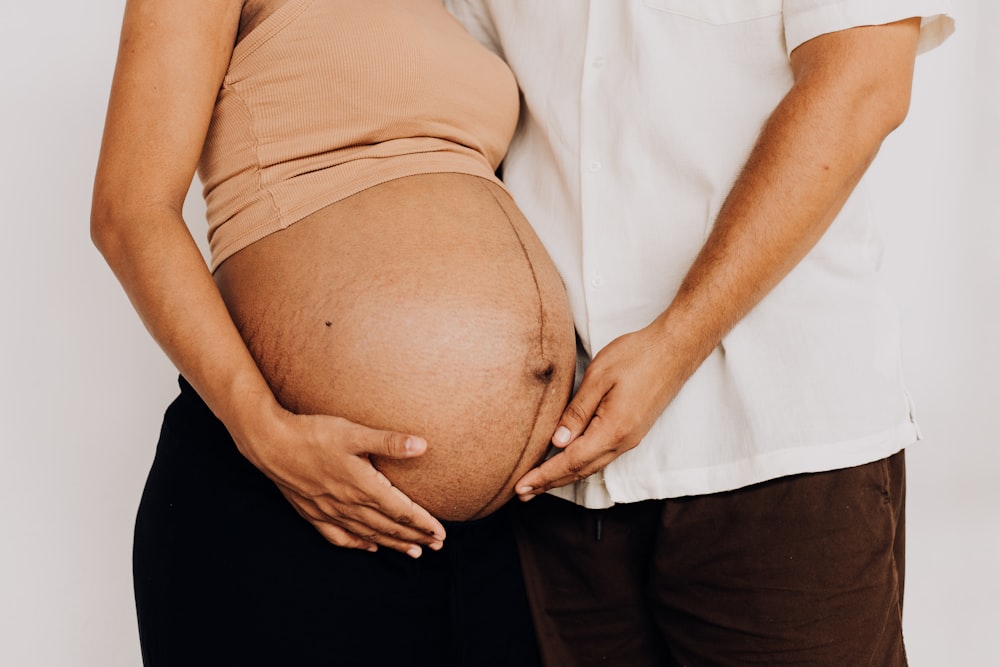 Ein Mann und eine Frau halten ihren schwangeren Bauch