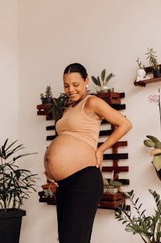 a pregnant woman standing in front of a plant
