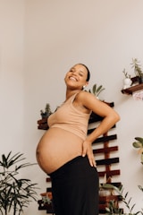 a pregnant woman standing in front of a plant