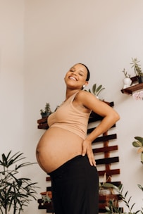 a pregnant woman standing in front of a plant
