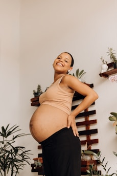 a pregnant woman standing in front of a plant