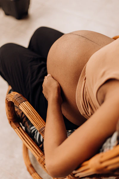 a pregnant woman sitting in a wicker chair