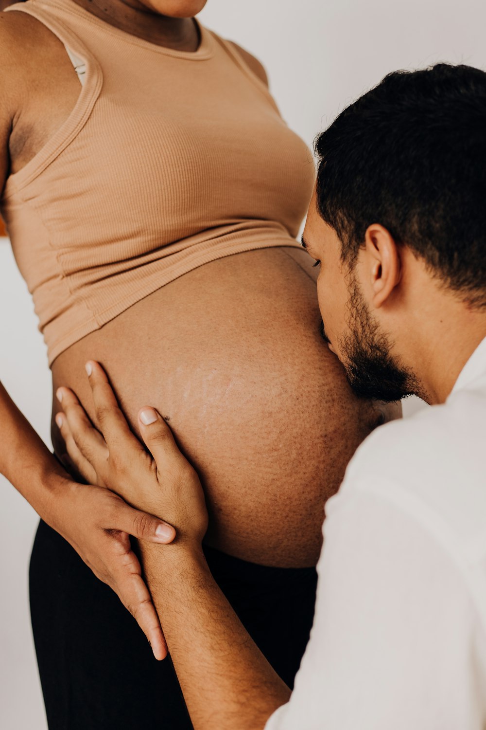 um homem grávida segurando sua barriga enquanto uma mulher olha para ele